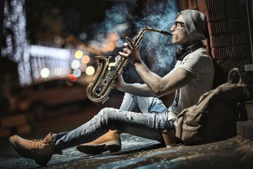A street musician plays the saxophone in the evening city