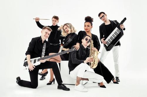 photo of multi ethnic music band in studio.Musicians and woman soloist posing over white background