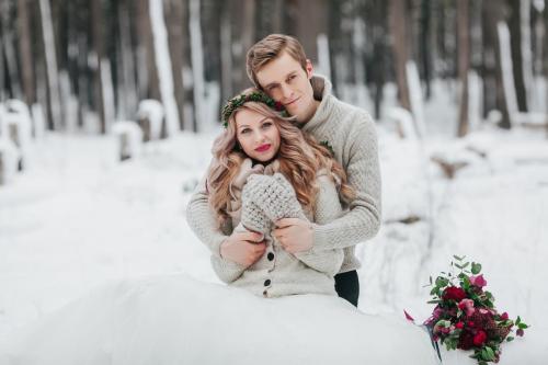 Newlyweds are hugging in the winter forest. Couple in love. Winter wedding ceremony.